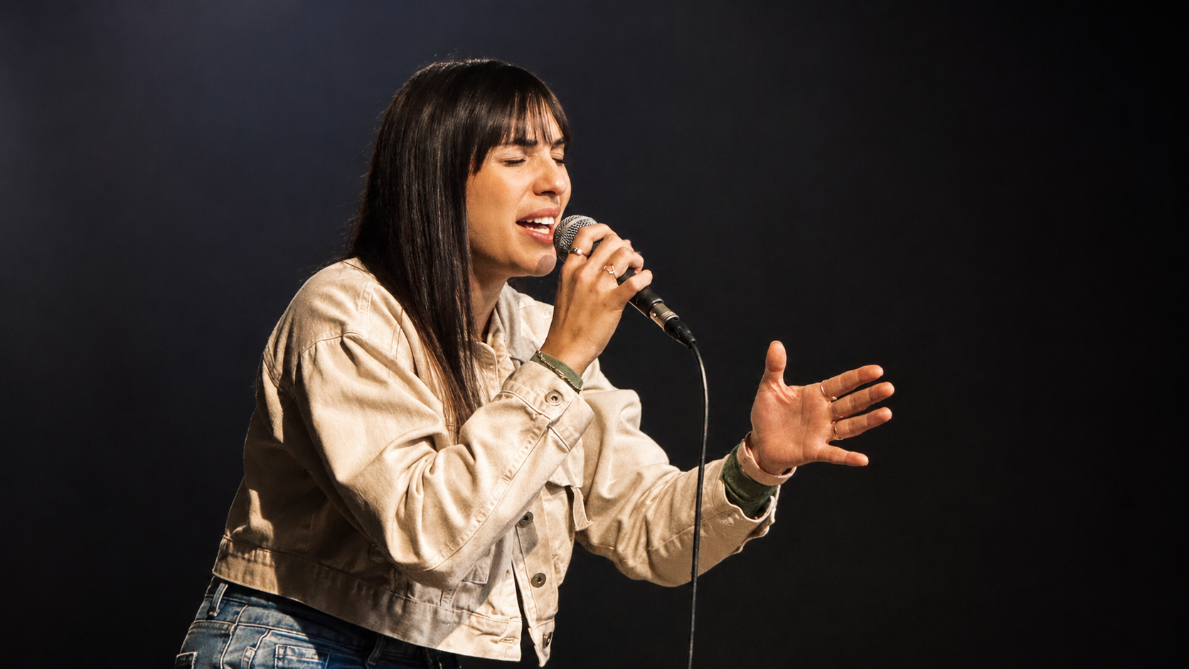 Mulher cantando ao microfone durante o louvor