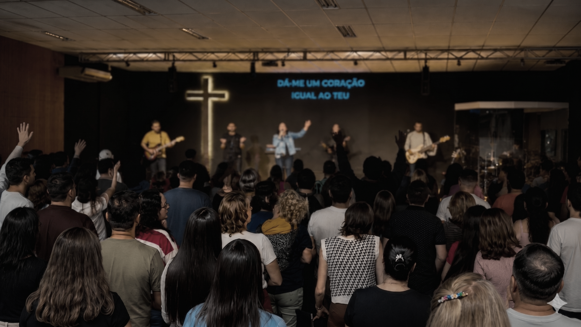 Congregação adorando durante o louvor com a frase 'Dá-me um coração igual ao teu'